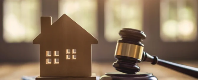 A wooden house model next to a gavel, symbolising houses sold at auction.