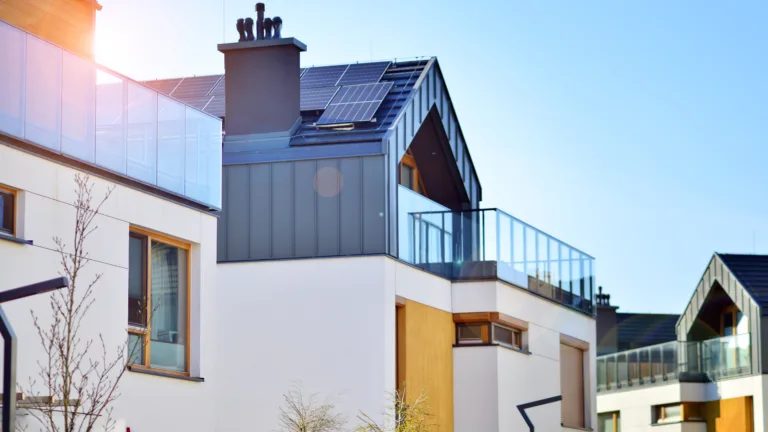 Modern home with solar panels on the roof under clear blue sky.