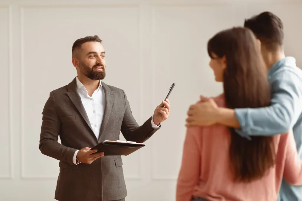 Professional estate agent conducting property viewing with couple in modern rental property