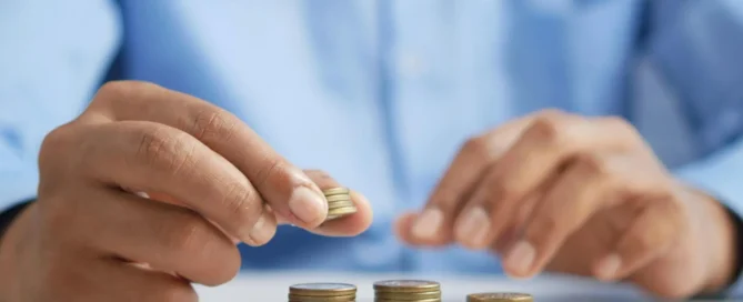 Person stacking gold coins representing property budget planning and autumn budget tax changes