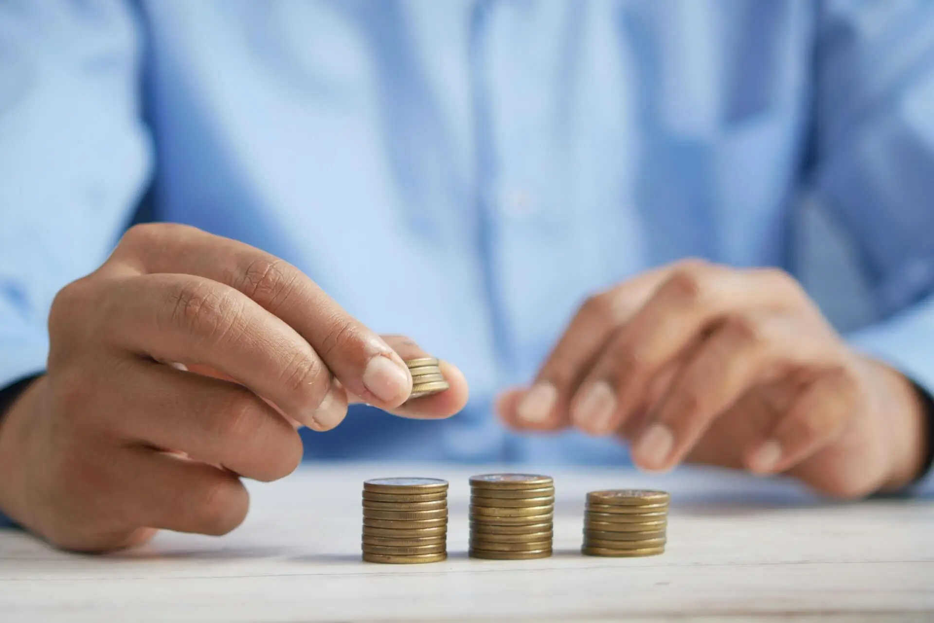 Person stacking gold coins representing property budget planning and autumn budget tax changes