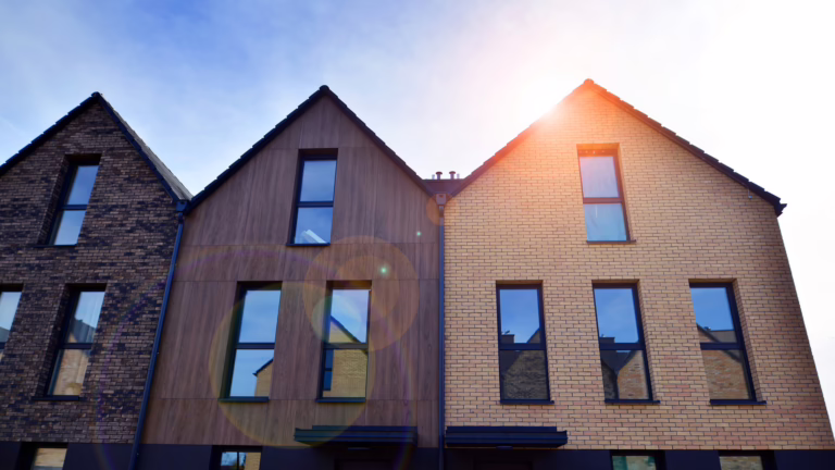 Modern row of newly built homes with brick and wood facades under bright sunlight.