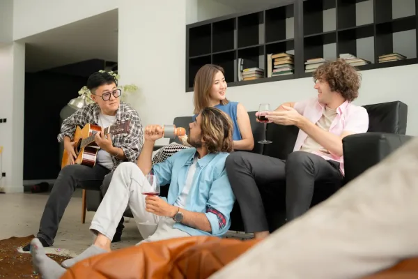 Multiethnic group of friends having fun playing guitar and singing together at home