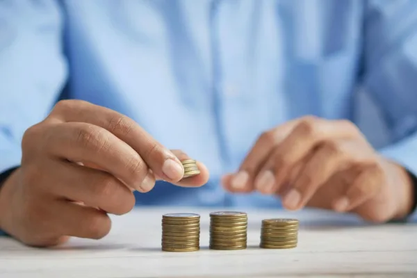 Person stacking gold coins representing property budget planning and autumn budget tax changes